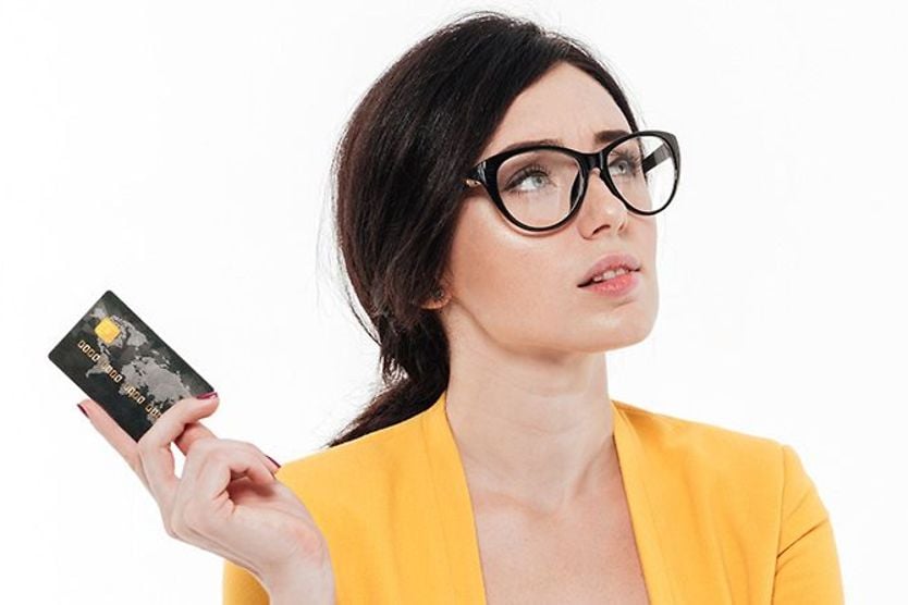 How much do glasses cost? Woman with eyeglasses holding a credit card looking perplexed