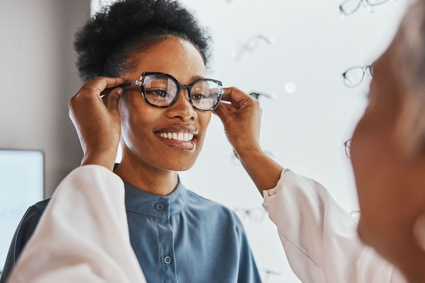 A woman getting fitted for eyeglasses at her optician's office, with special attention to frame temple size. A woman getting fitted for eyeglasses at her optician's office, with special attention to frame temple size.