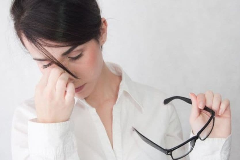 5 signs your glasses don’t fit Woman with eye strain holding glasses