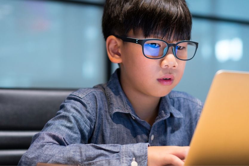 Do blue light filtering glasses work? young boy wearing blue light blocking glasses looking at laptop screen