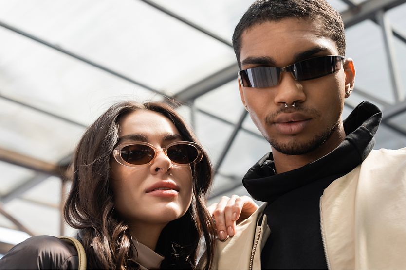 man and woman on beach wearing sunglasses