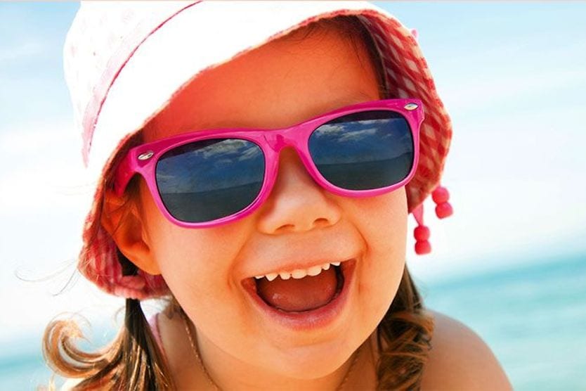 child wearing sunglasses and sun hat at the beach