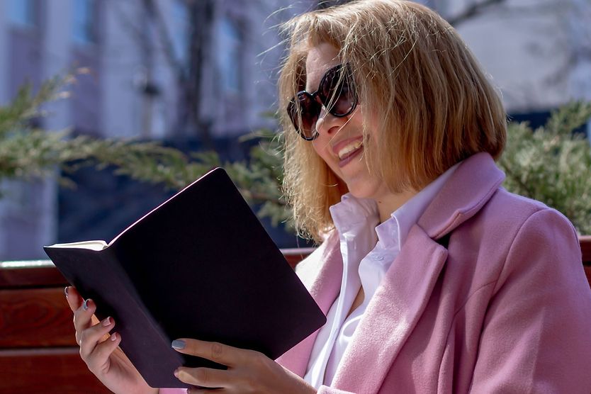woman reading a book outside wearing reading sunglasses