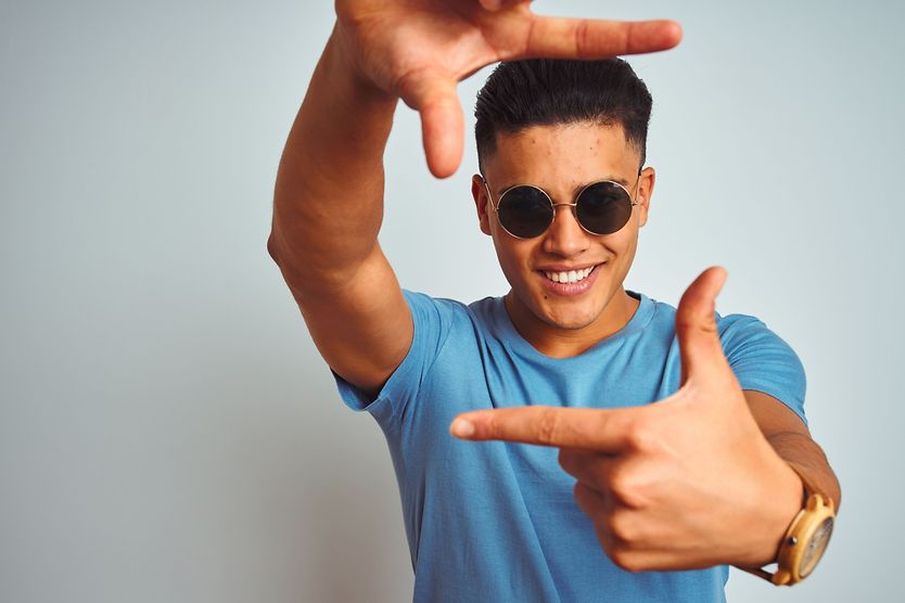 Men’s sunglasses: Which are best for your face shape? man wearing sunglasses with his fingers extended out to frame his face