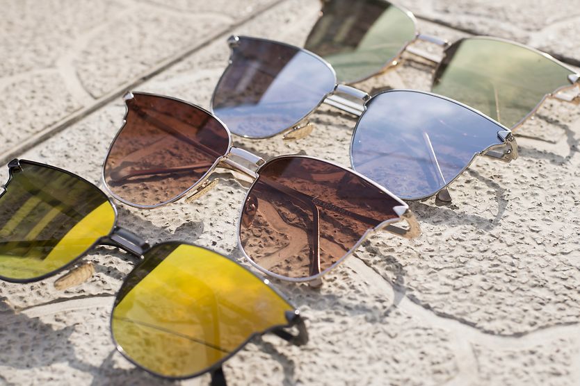 How should your Aviator sunglasses fit? different colored sunglass lenses on concrete