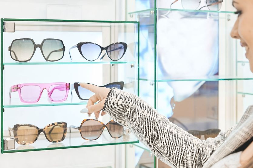 woman choosing between plastic or glass sunglass lenses
