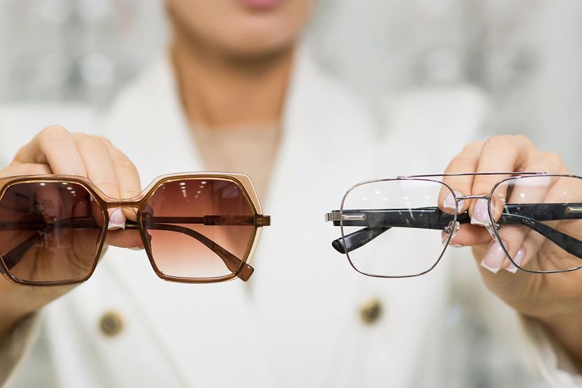 woman holding sunglasses and glasses in hands