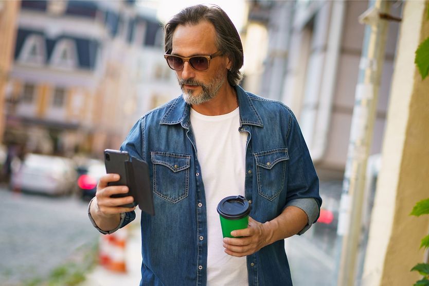 Man wearing progressive sunglasses outdoors looking at mobile phone
