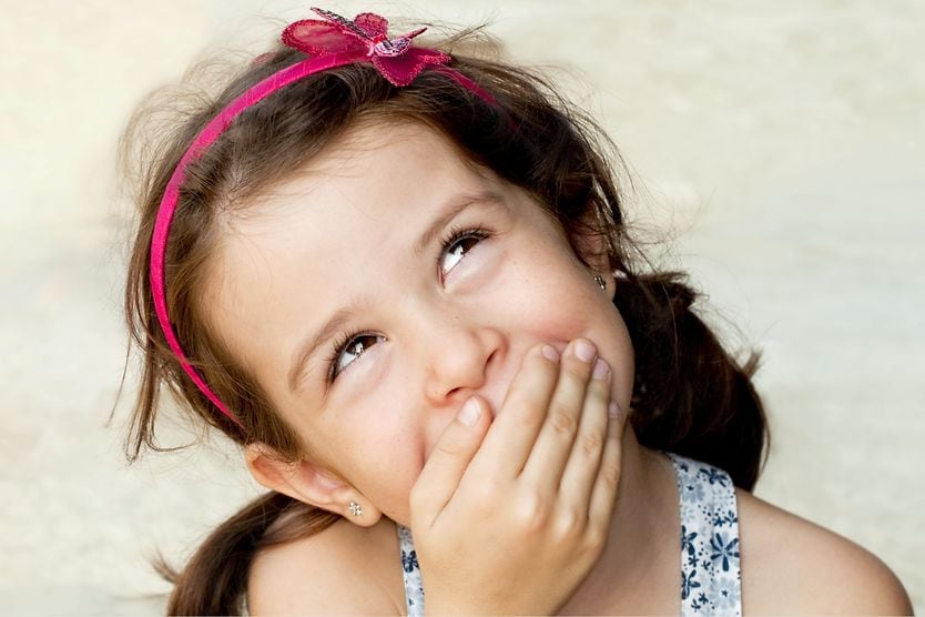 Eye movement and lying: Genuine or junk science? lying young girl looking up and covering her mouth