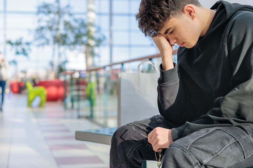 Sensory overload: A guide for people with low vision teen boy sitting on bench overwhelmed with glasses in hand