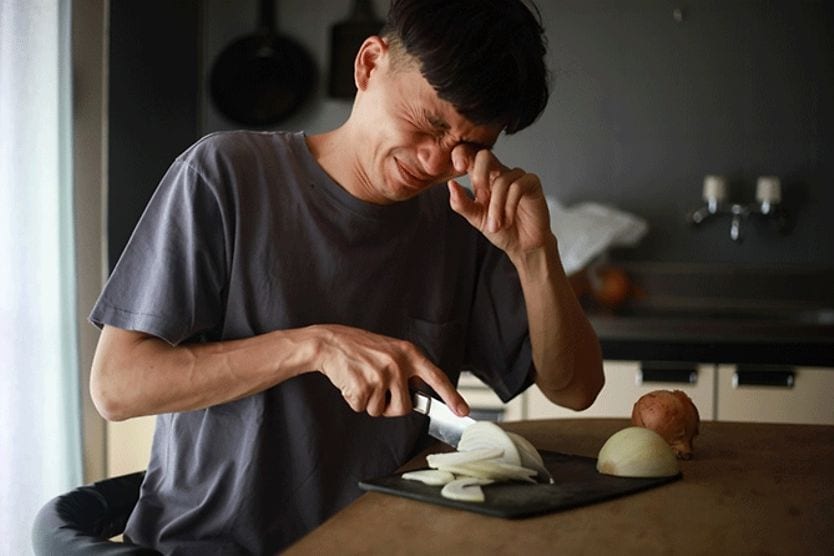man cutting onions and crying