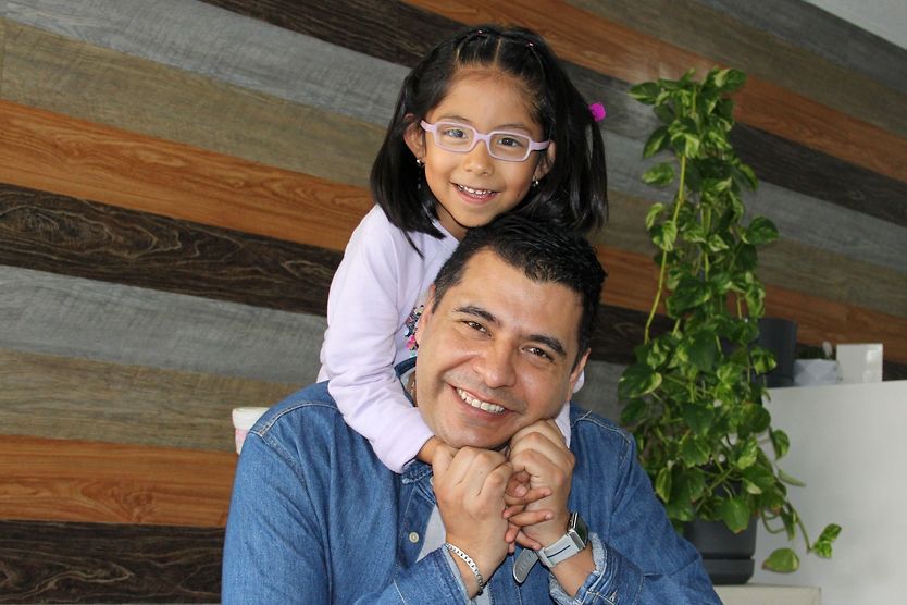 young girl wearing glasses hugging her father
