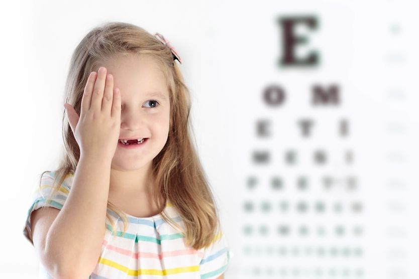 Child covering her eye at an eye exam.