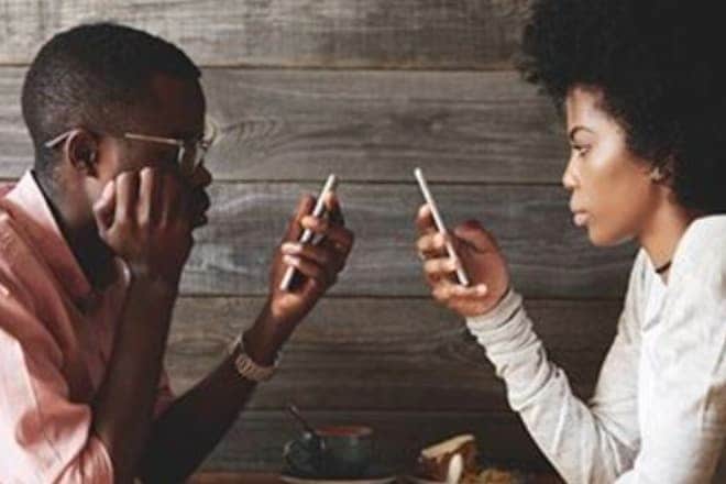 young man and woman looking at their cell phones