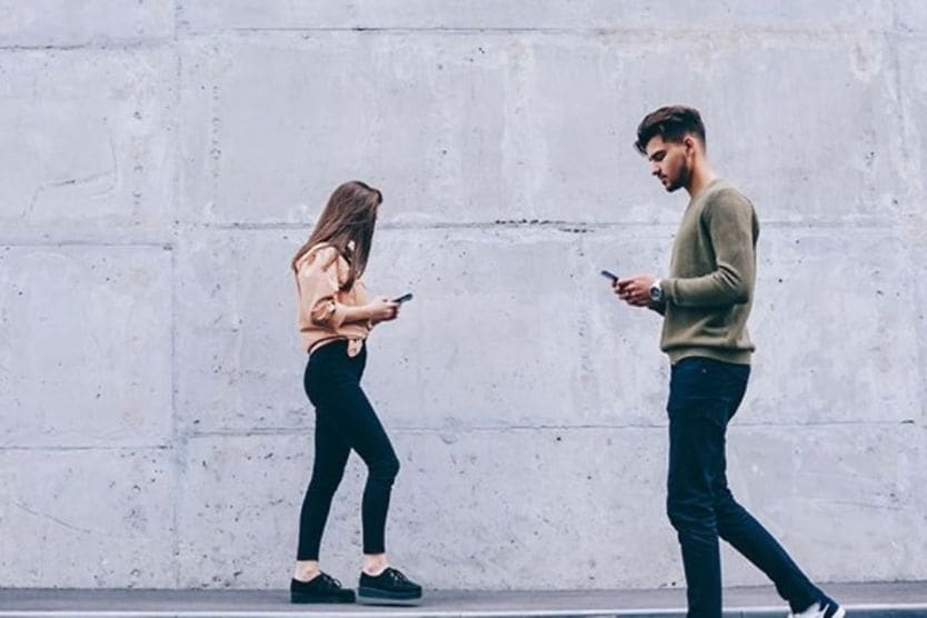 young man and woman looking at their cell phones