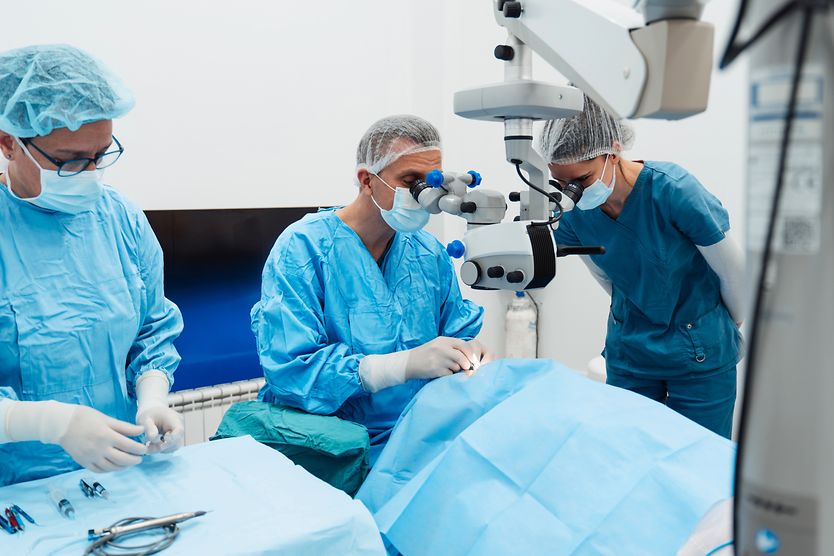 Two eye care professionals and one eye surgeon performing cataract surgery on a patient. Two eye care professionals and one eye surgeon performing cataract surgery on a patient.