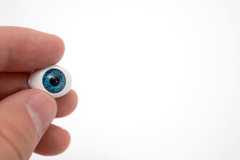 Tooth in eye surgery Prosthetic eyeball in hand on white background.