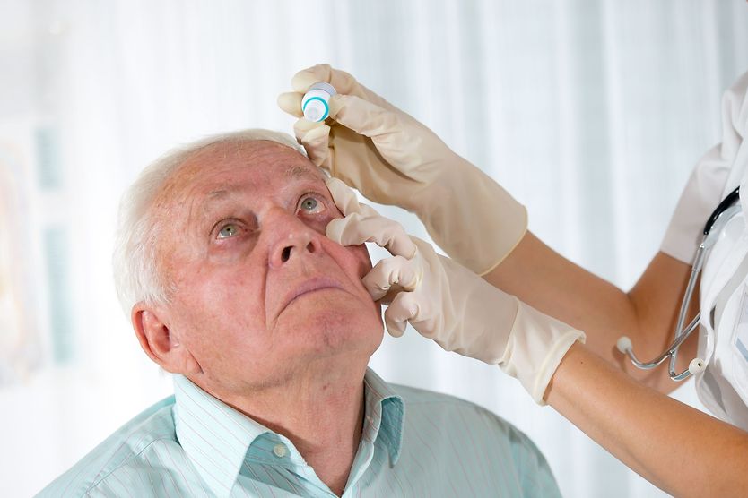 doctor putting eye drops in man's eyes older man with glaucoma getting eye drops as glaucoma treatment