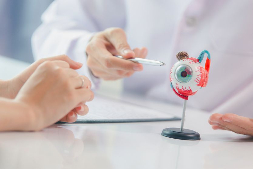 eye doctor using anatomical model of an eye to explain surgery