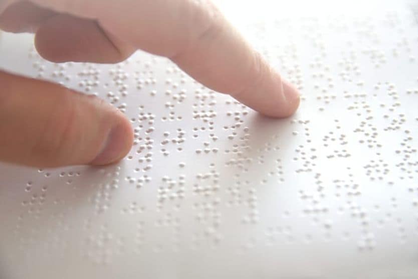 Primo piano di una persona che legge in Braille passando il dito su una pagina, a sottolineare la grave perdita della vista che può derivare dalle complicanze della miopia.