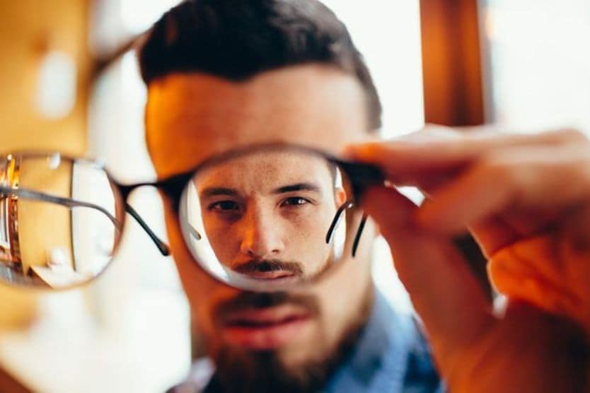 Uomo che guarda attraverso la lente degli occhiali Uomo che guarda attraverso la lente degli occhiali