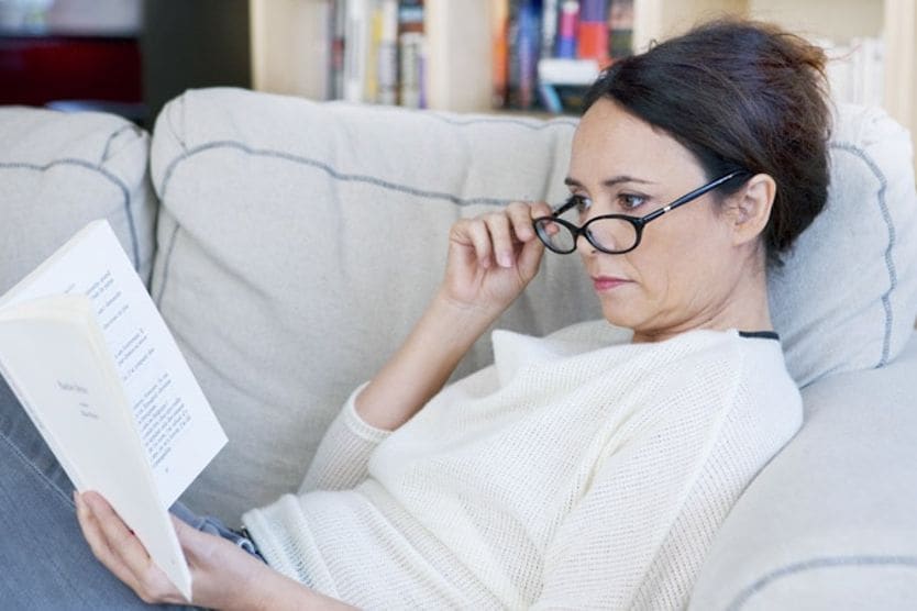 Donna con occhiali da vista che legge un libro Donna con occhiali da vista che legge un libro