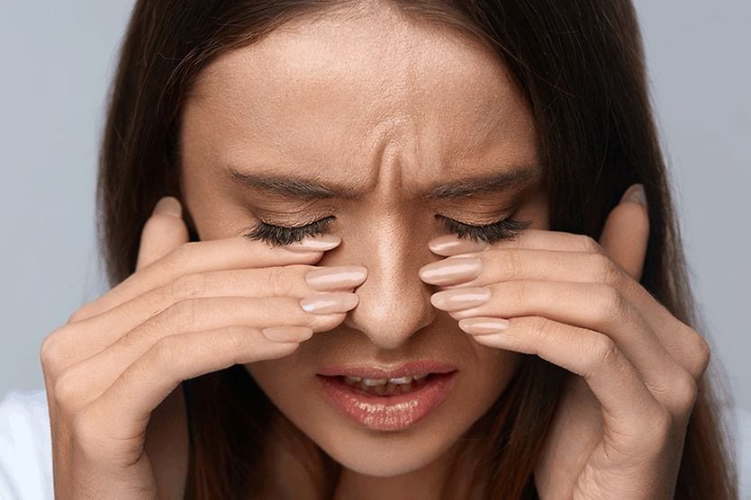La donna ha le dita sugli occhi per la sensazione di bruciore