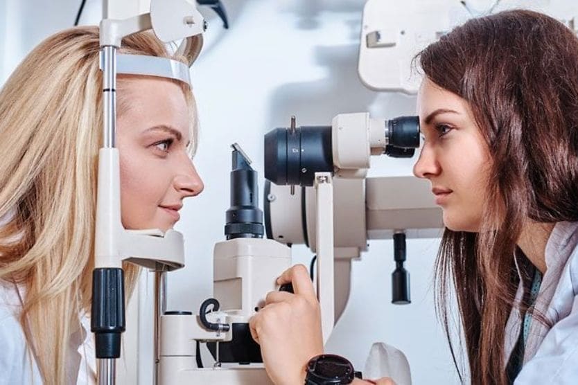 Donna che esegue una visita oculistica su un'altra donna Donna che esegue una visita oculistica su un'altra donna