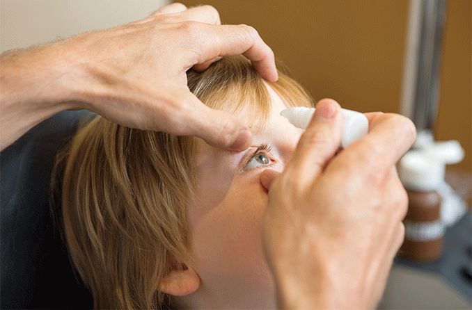 child getting atropine eye drops put into their eyes