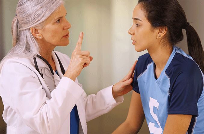 girl with a head injury getting eyes checked by a doctor