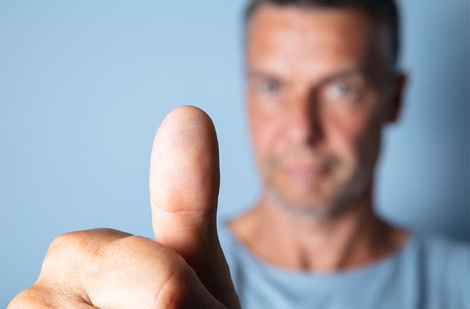 man holding thumb out focusing on astigmatism eye exercises