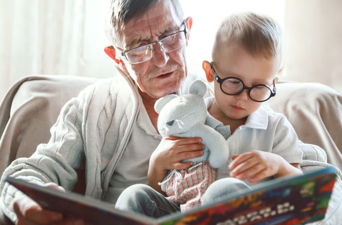 grandfather reading a book to his grandson