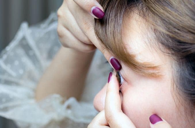 Young, dark-haired woman inserting a contact lens