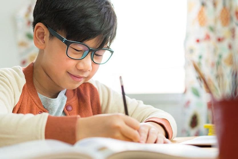 Cậu bé đeo kính làm bài tập về nhà Cậu bé đeo kính làm bài tập về nhà