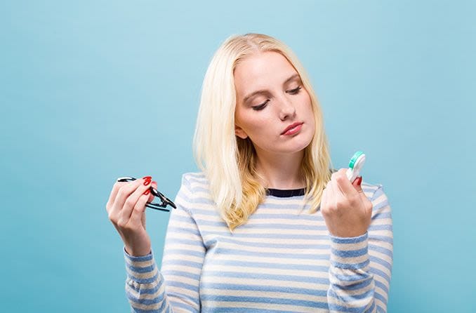 woman looking perplexed trying to decide between contacts or glasses