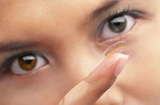 woman putting in colored contacts for her astigmatism