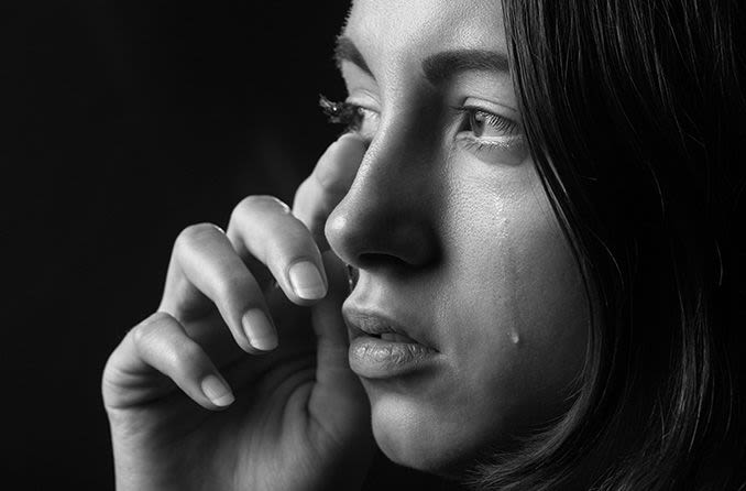 woman wiping her tears away from her eye