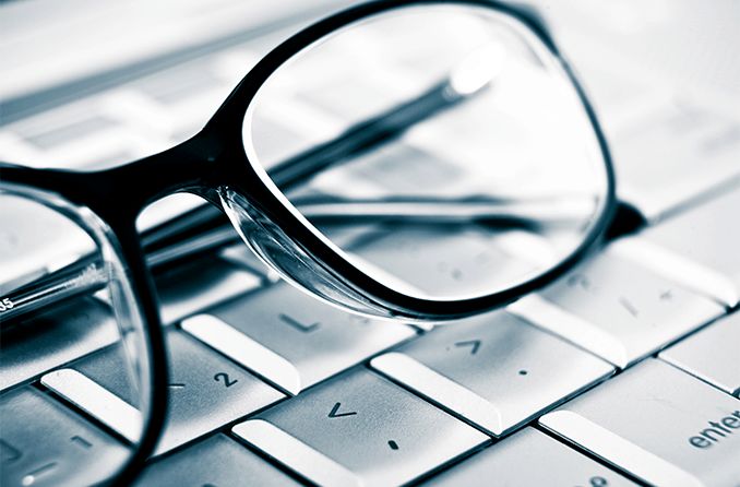 pair of prescription eyeglasses on top of computer keyboard