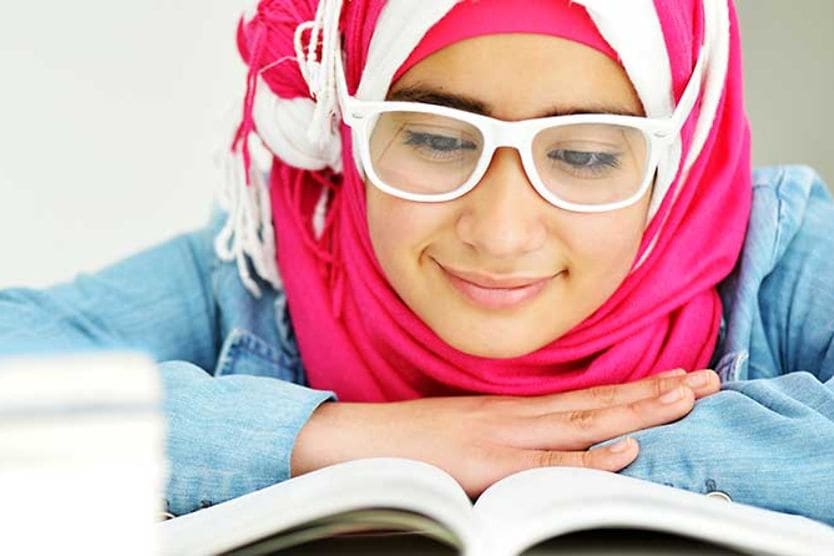 فتاة صغيرة ترتدي نظارة تقرأ كتابًا