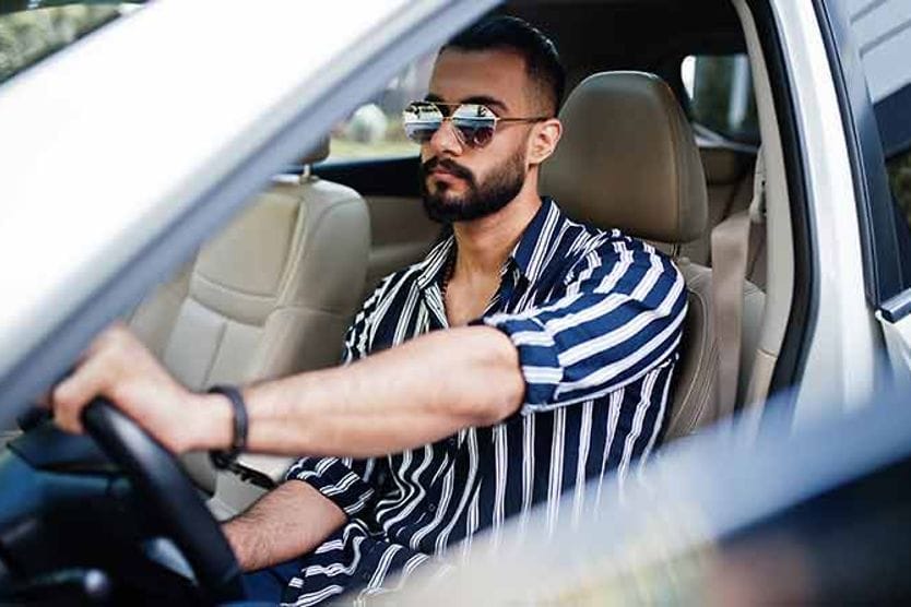 رجل يقود يرتدي النظارات الشمسية