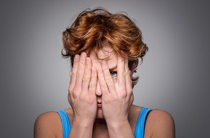 Woman with an eye disorder covering her face with her hands