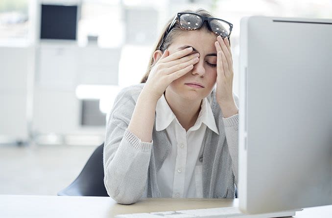 woman at a computer rubbing tired eyes