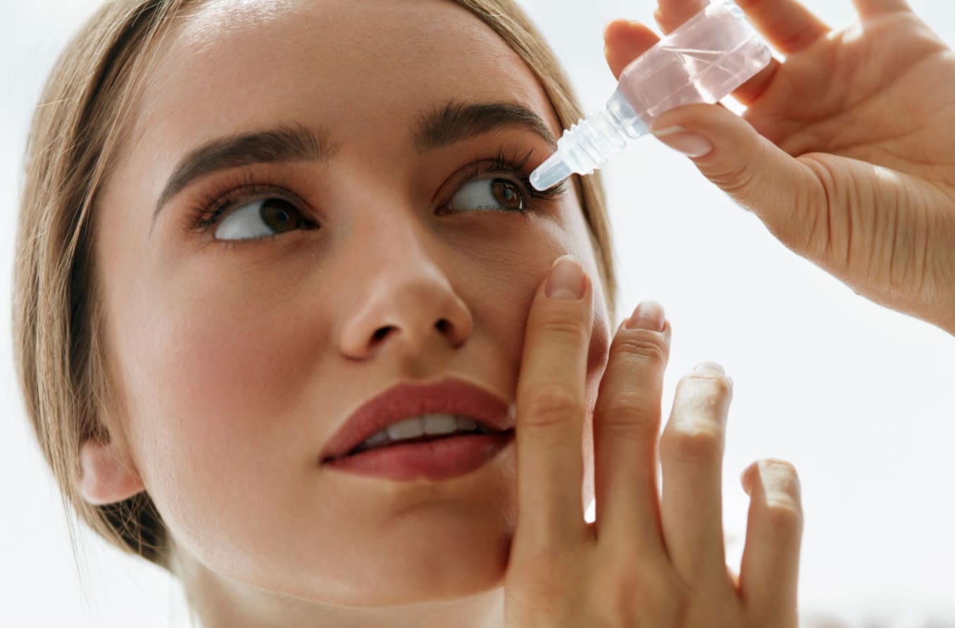 Person placing eye drops into eye