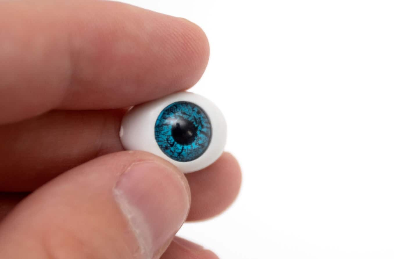 Prosthetic eyeball in hand on white background.