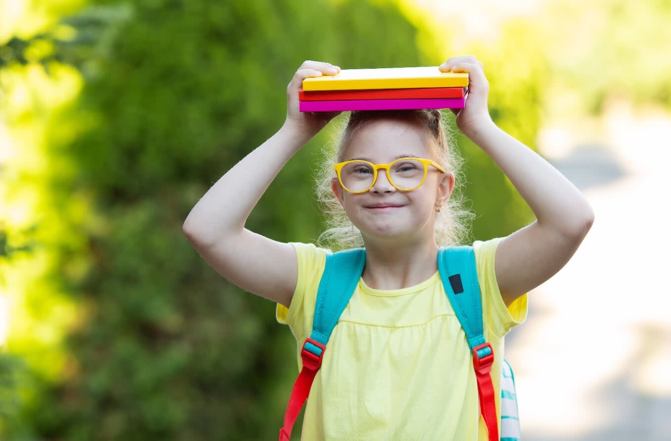 Little girl holding books and wearing a backpack