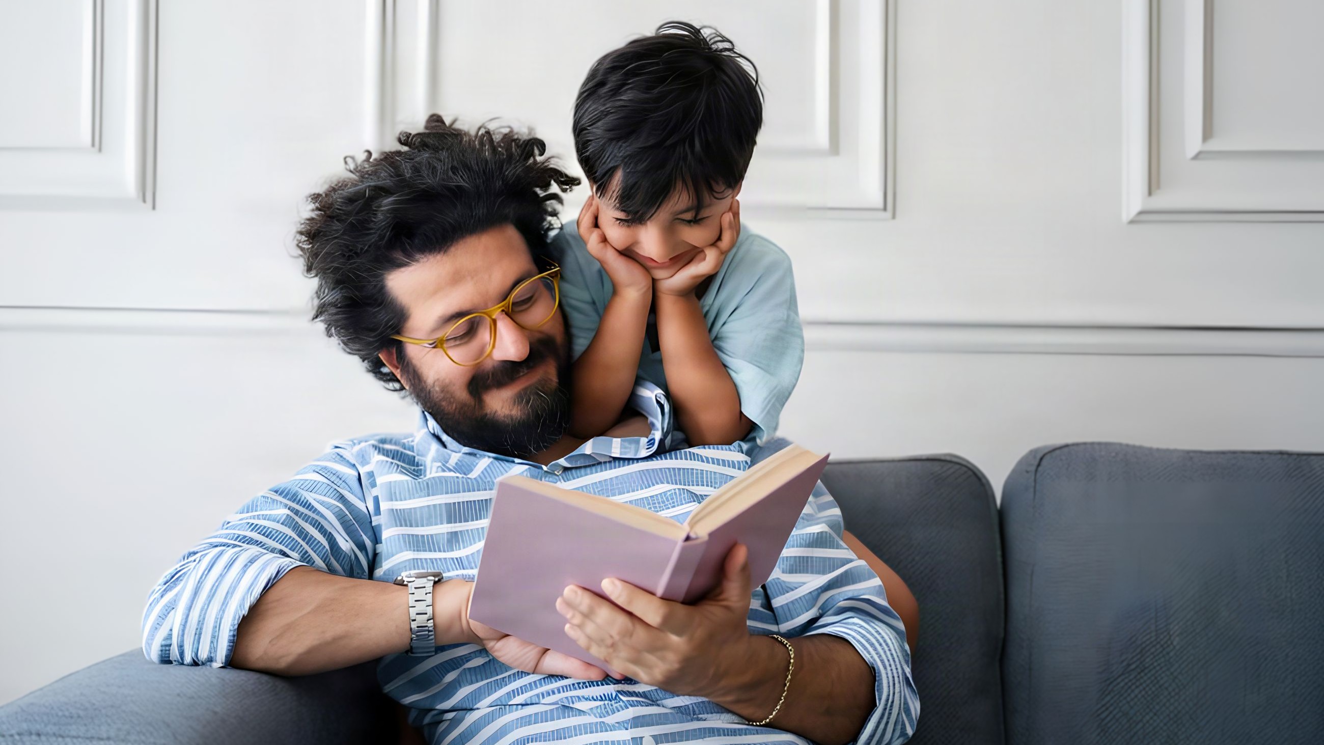 father reading book to his child on the couch