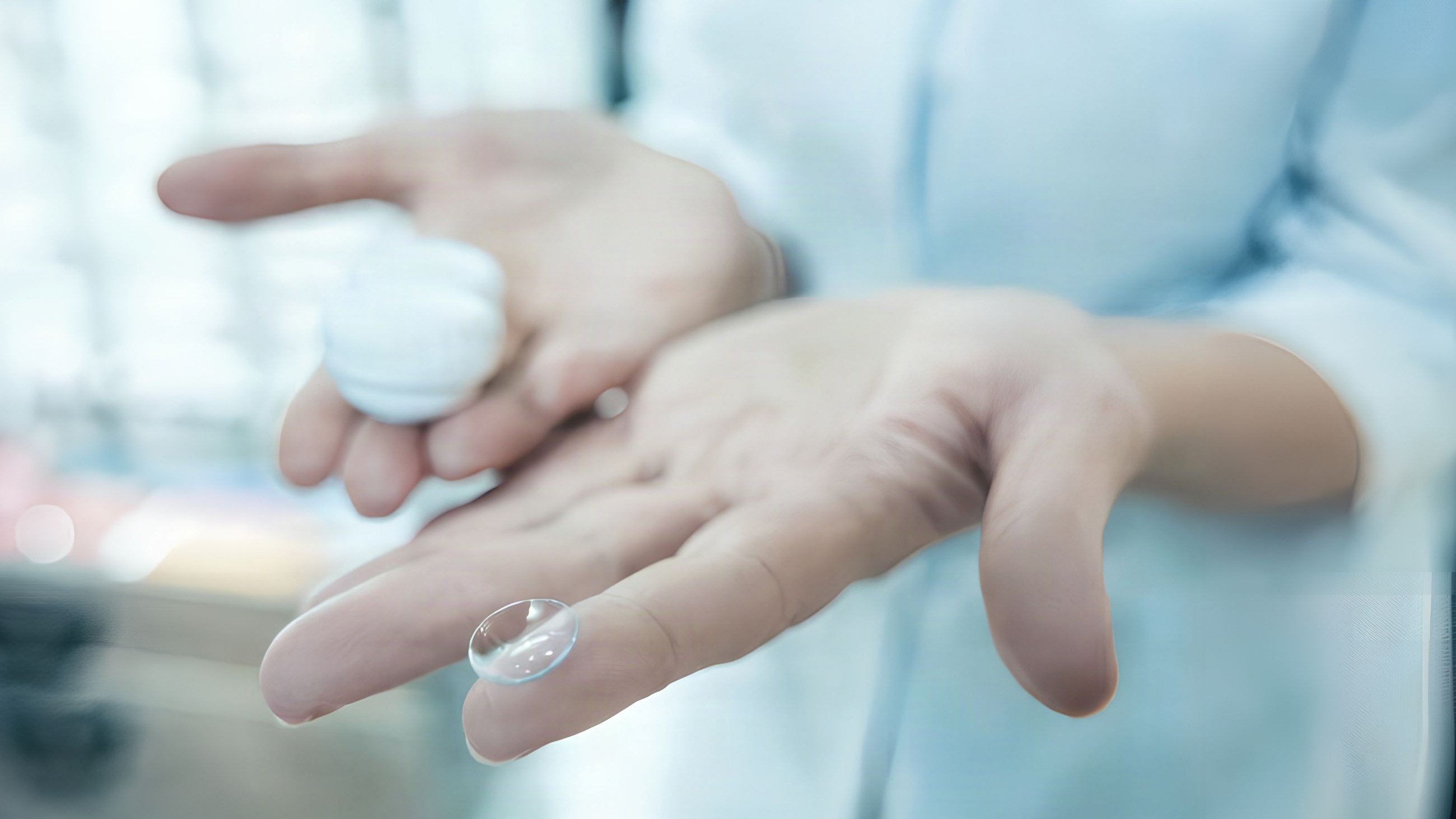 Person holding out hands with contact lenses and case in hands.