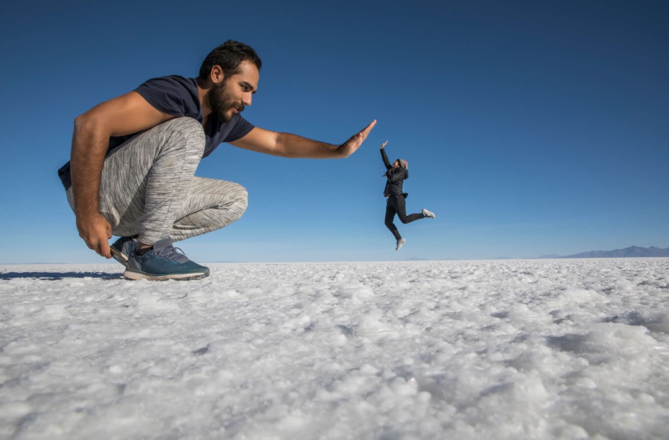 Optical illusion of giant man and small woman high-fiving.