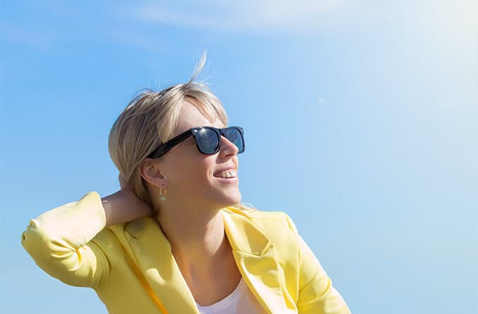 woman wearing Ray-ban sunglasses looking up at sun