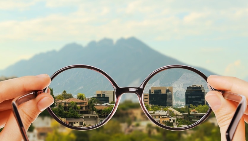 Looking through glasses at a mountain landscape, showing the difference between myopia and corrected vision through the lenses.